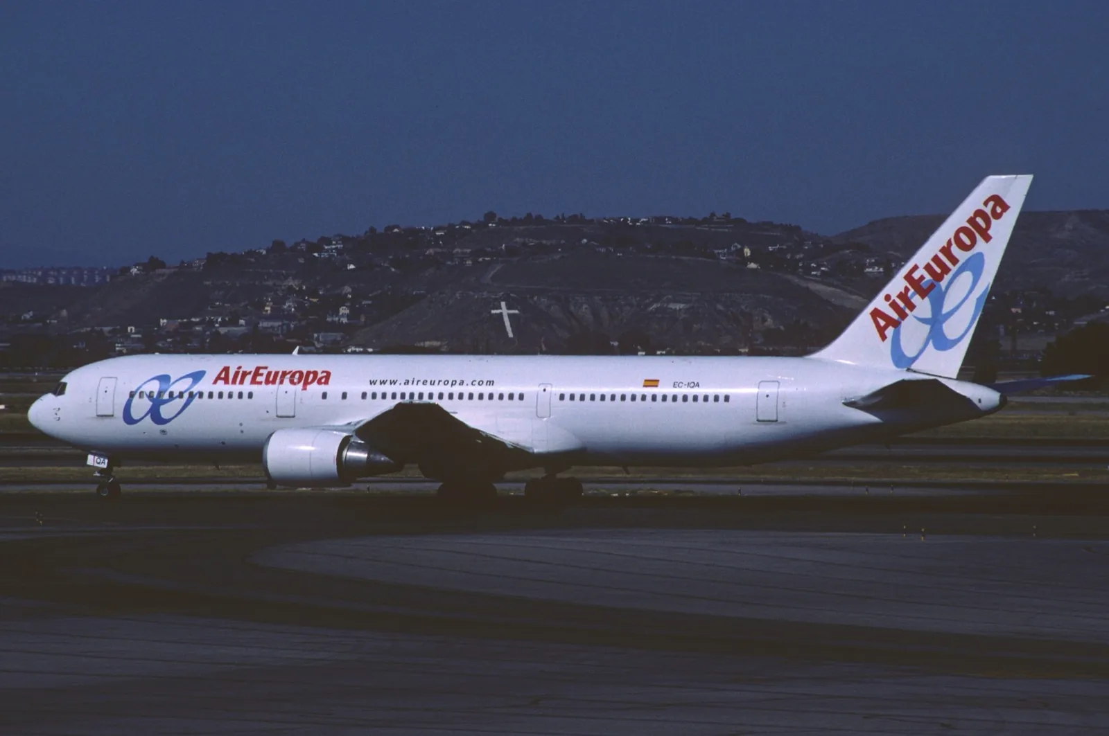 Air Europa Boeing 767-300 EC-IQA taxiing at Madrid in low evening light, houses on a hillside behind