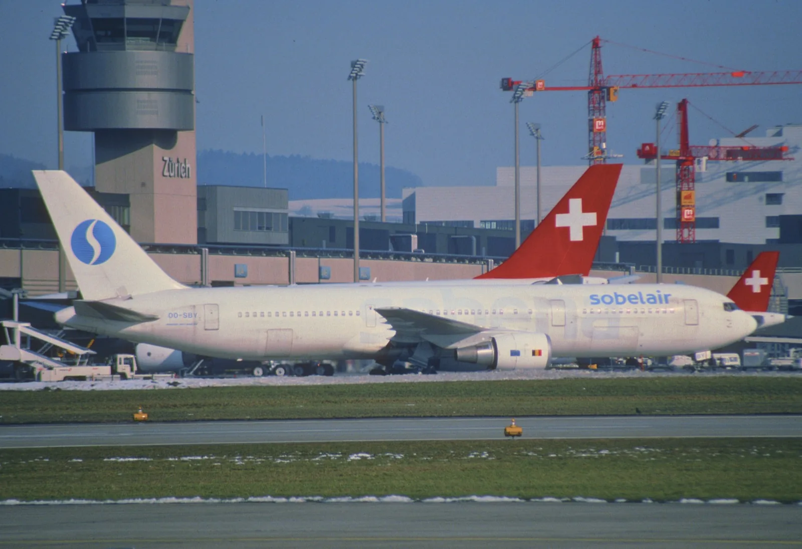 Sobelair Boeing 767-300ER OO-SBY parked on a snowy apron at Zurich, a Sabena-style S on its tail and a Swissair tail behind it