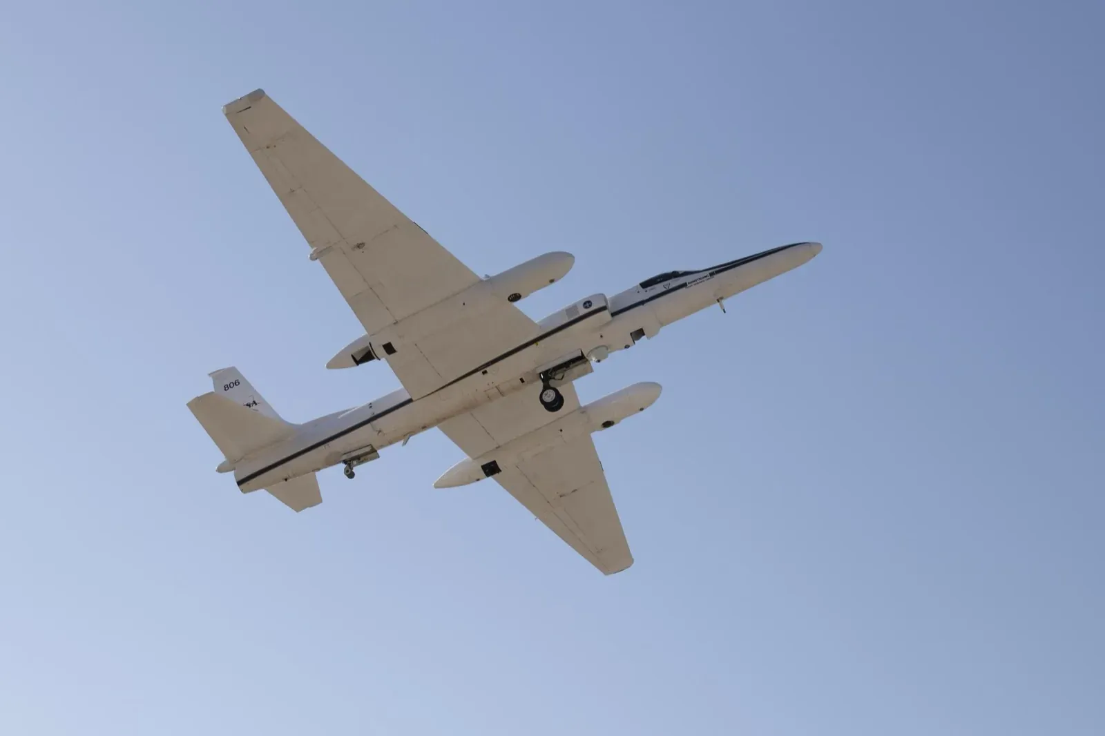 The underside of ER-2 number 806 passing directly overhead against a blue sky, wing pods visible