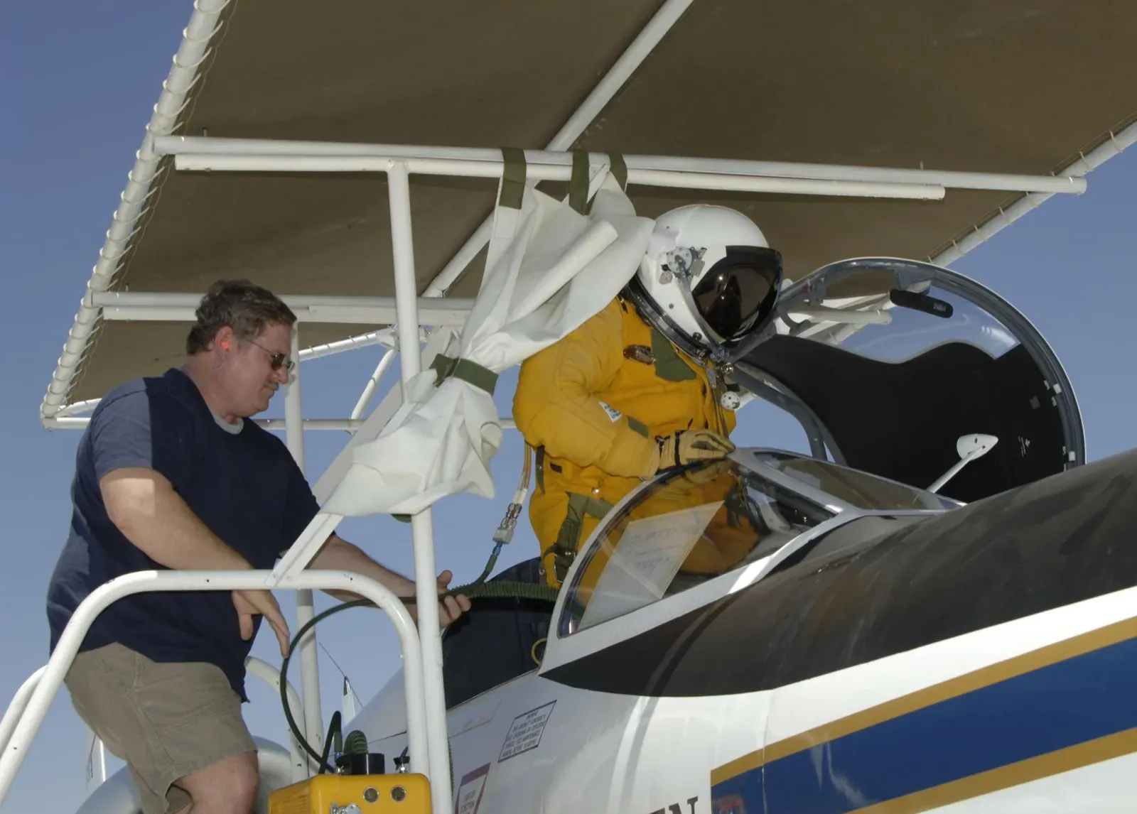 A pilot in a yellow full-pressure suit climbing into the ER-2's cockpit, assisted by a life-support technician