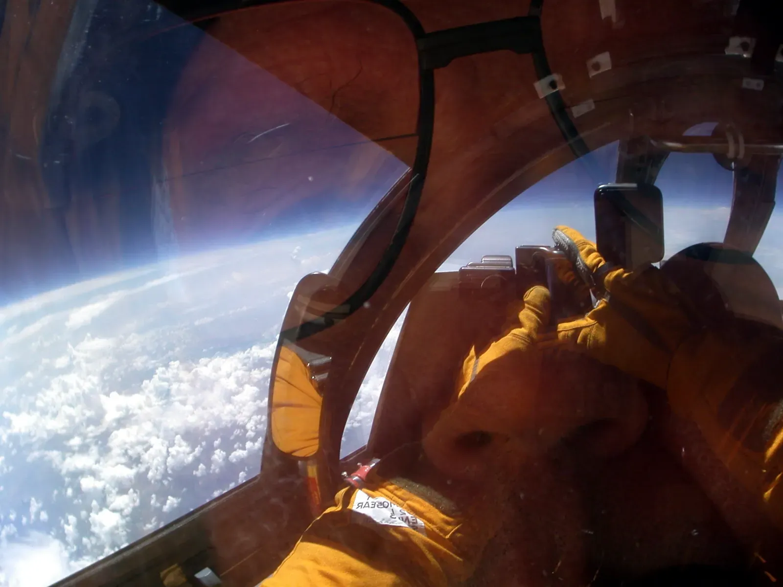 The view from the ER-2's cockpit: a curved horizon, a thin band of blue atmosphere, and a cloud deck far below