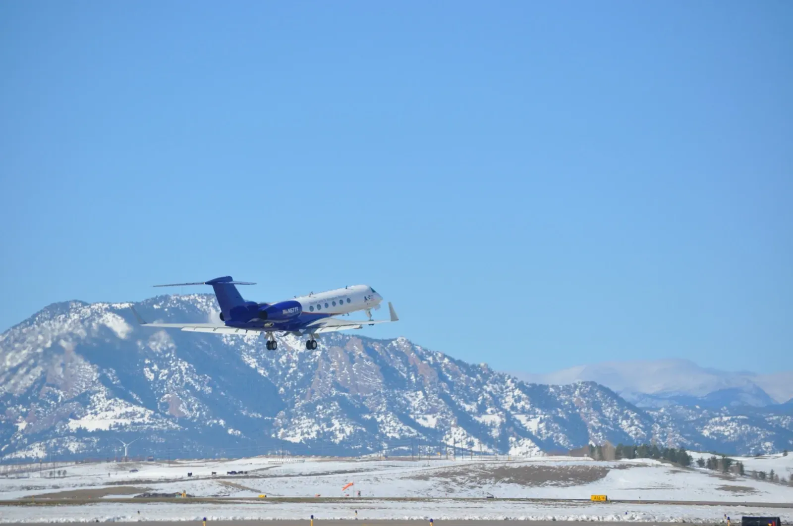 The NSF/NCAR Gulfstream V research aircraft lifting off, with the snow-covered Flatirons behind it
