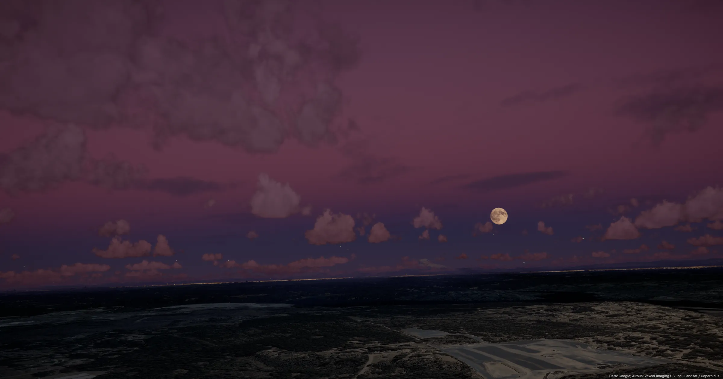 A full moon in a plum-coloured twilight sky, low clouds catching the last light above a darkened coastline