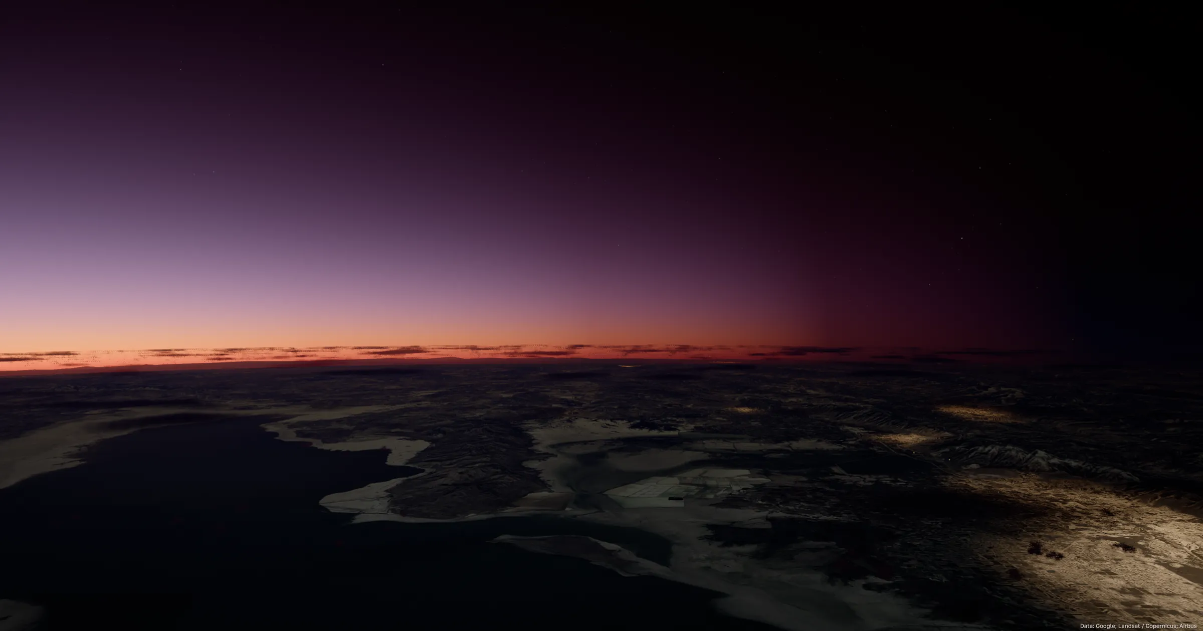 A narrow red-orange sunset band along the horizon under a deep purple sky, a dark bay and snow-covered land far below